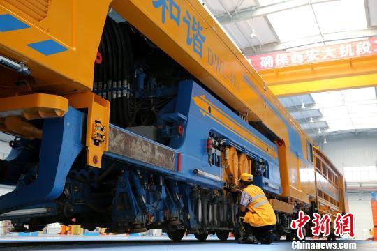 圖為工人正在清理大型養(yǎng)路機械。　張遠 攝